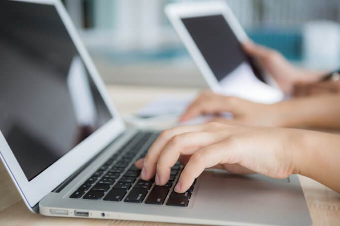 close up of woman's hands typing on a laptop